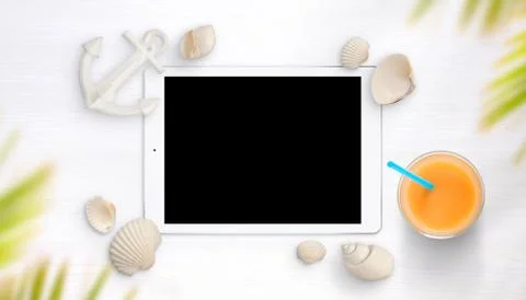 Tablet surrounded with shells on white table. Juice and small boat anchor bes Stock Photos