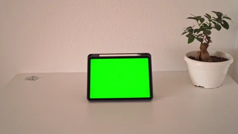 Tablet on table with green screen in home setting during daylight hours Stockbeeldmateriaal 339585310