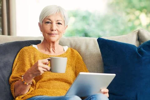Tablet, tea and portrait of old woman in home to relax, news article or dig.. Stock Photos