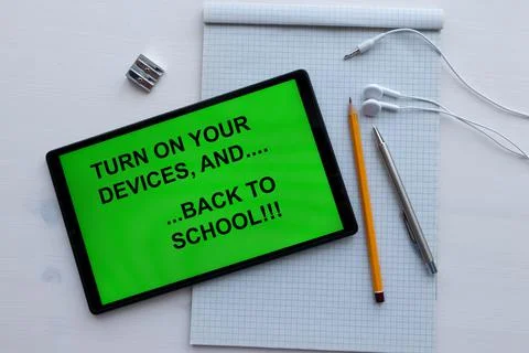 Tablet with text "turn on your devices ... and back to school" on the screen, ne Stock Photos