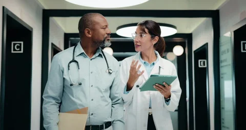 Tablet, walking and doctors at clinic for planning, schedule discussion or Stock Footage 335437102