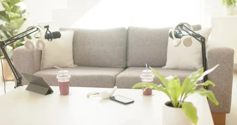 Tabletop and sofa podcast set showing mic boom arms, headphones, cups shifting Stock Footage 337225057