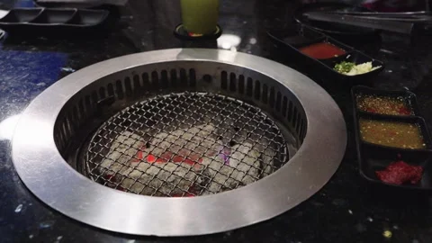 Tabletop charcoal grill with glowing red embers at a Korean barbecue restau.. Video stock 335359280