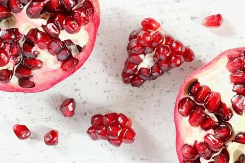 Tabletop closeup view - pomegranate half, clusters of gem like fruits scatter Stock Photos