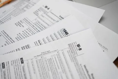 Tabletop cluttered with diverse tax forms signifying annual tax preparation Stock-Fotos