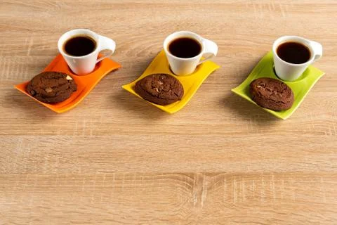 Tabletop perspective on three cups of espresso and chocolate biscuits Stock Photos