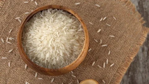 Tabletop of raw white rice rotating on burlap. Rustic wooden background Video stock 70030269