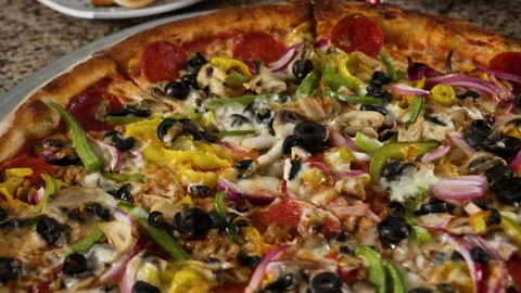 Tabletop shot of large supreme pizza fully covered in vegetables and Stock Footage 201477427