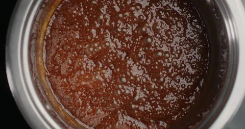 Tabletop slow motion video: Melted sugar is boiling in the metal bowl on the hot Stock Footage 133419853