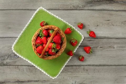 Tabletop view, small basket full of strawberries, some of them spilled on gre Stock Photos