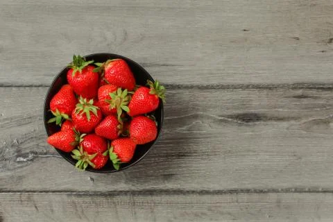 Tabletop view - small black ceramic bowl with freshly picked strawberries, on Stock Photos