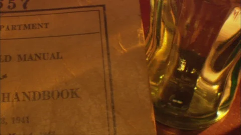 Tabletop - WW2 era Coke Bottle and U.S. Army "Soldier's Handbook" at night. Video stock 91293555