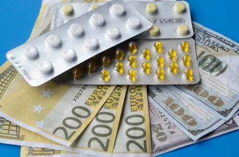Tablets and banknotes. The concept of imposing medical drugs. Stock Photos