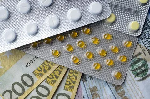 Tablets and banknotes. The concept of imposing medical drugs. Stock Photos