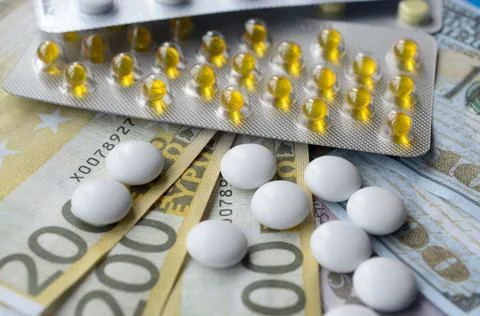 Tablets and banknotes. The concept of imposing medical drugs. Stock Photos