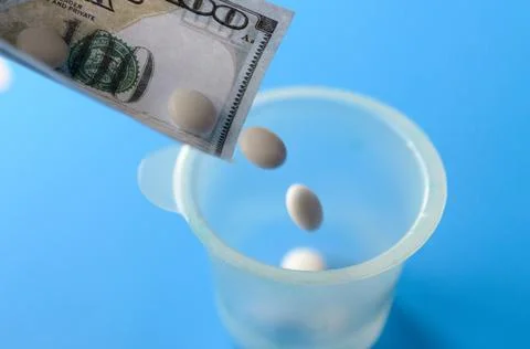 Tablets and banknotes. The concept of imposing medical drugs. Stock Photos