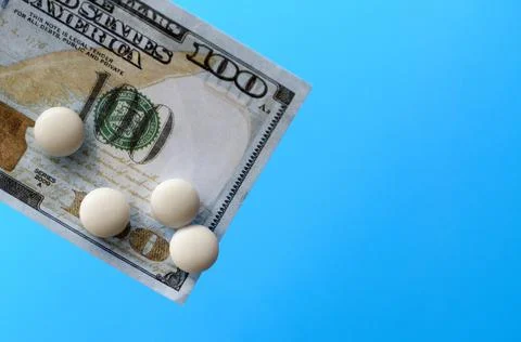 Tablets and banknotes. The concept of imposing medical drugs. Stock Photos