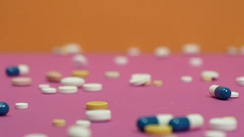 Tablets and capsules rained down on pink and orange background. Видео 126555878