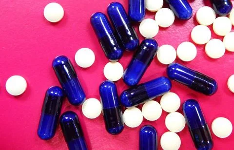 Tablets and capsules on a red background Stock Photos
