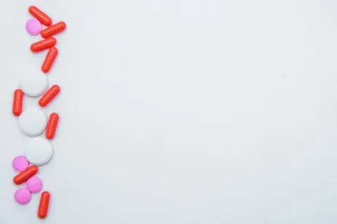 Tablets and capsules of white and pink color lie on the side on a white Stock Photos