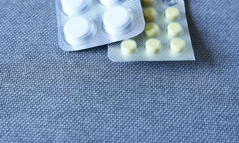 Tablets and pills packed in blisters on blue fabric background, closeup Stock Photos