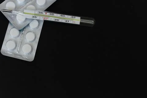 Tablets and a thermometer on a black background Stock Photos