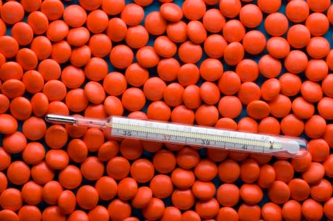 Tablets and thermometer close up on blue Stock Photos