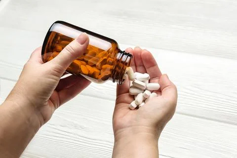 The tablets are poured from the bottle into the open palm. Foto stock