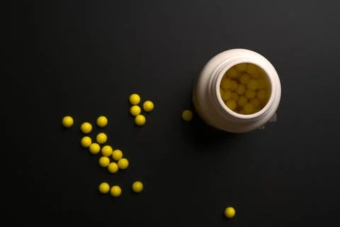 Tablets with a bottle of them on a black background. Stock Photos