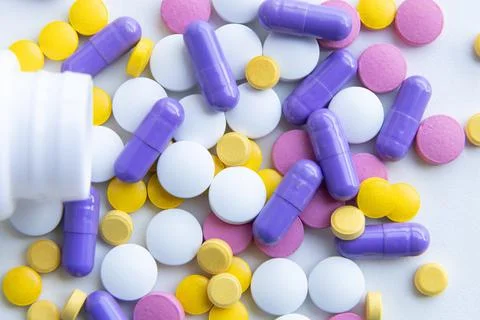 Tablets of different types and colors, tablets fell out of the container Stock Photos
