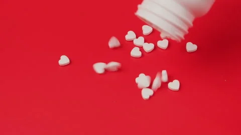 Tablets falling out of white plastic tube with an open cap on a red studio table Stock Footage 278344374