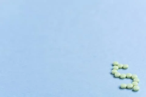 Tablets in the form of a dollar sign on a blue background. Concept of a dolla Stock Photos