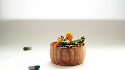Tablets with herbal medicines fall into a plate with medicinal herbs. Stock Footage 169178770