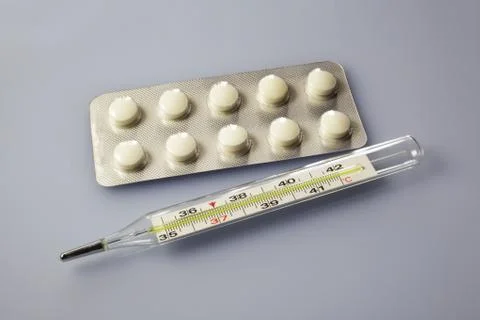 Tablets lie next to a thermometer Foto stock