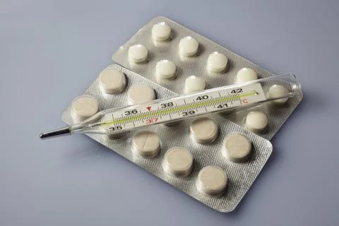 Tablets lie next to a thermometer Stock Photos