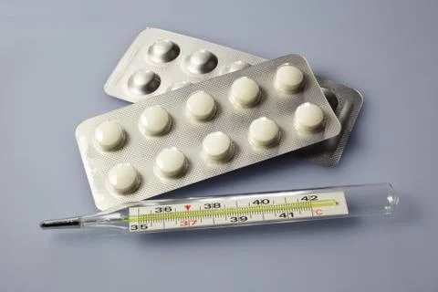 Tablets lie next to a thermometer Foto stock