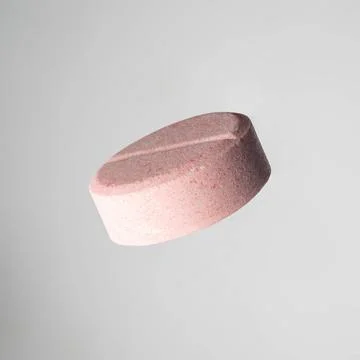 Tablets on a light background one pink medical ascorbic pill on light grey... Stock Photos