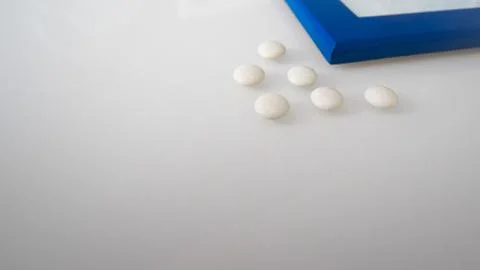 Tablets or sweets, white and colored on a white glass table Foto stock