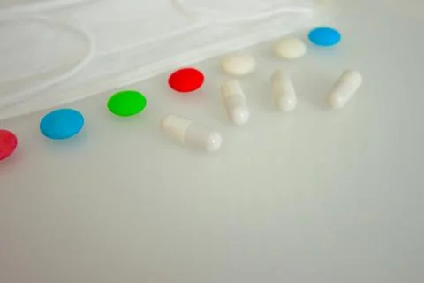 Tablets or sweets, white and colored on a white glass table Stock Photos