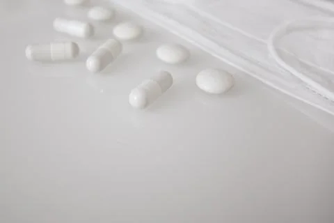 Tablets or sweets, white and colored on a white glass table Stock Photos