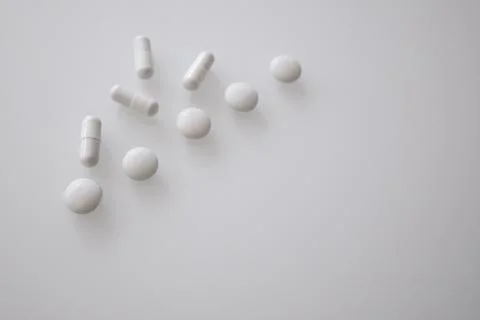 Tablets or sweets, white and colored on a white glass table Foto stock