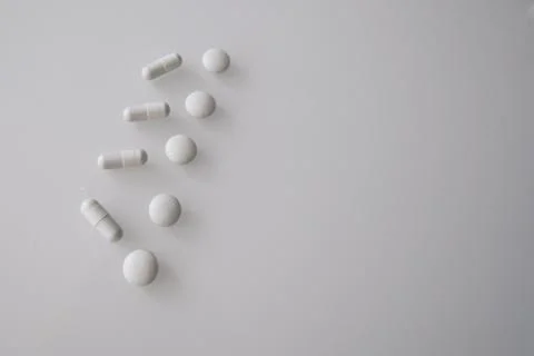 Tablets or sweets, white and colored on a white glass table Stock Photos