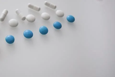 Tablets or sweets, white and colored on a white glass table Stock Photos