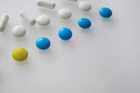 Tablets or sweets, white and colored on a white glass table Stock Photos