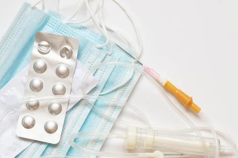 Tablets in a package and a dropper lie on medical masks on a white background Foto stock