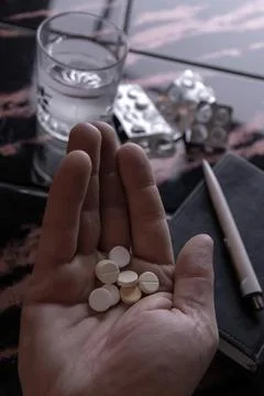 Tablets in a person's hand against a background of empty blisters, a glass of Stock Photos