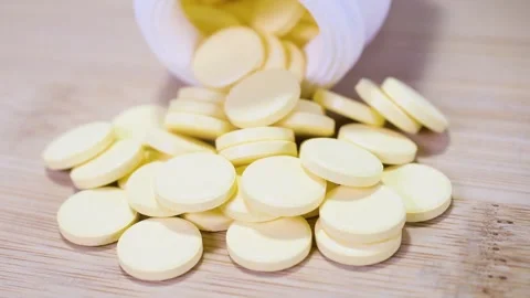 Tablets pills spilling from plastic pill bottle on natural background Video stock 259541336