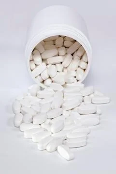 Tablets spilling from container Stock Photos