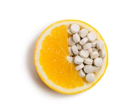 Tablets with vitamins in an orange slice. Isolated on white background. Stock Photos