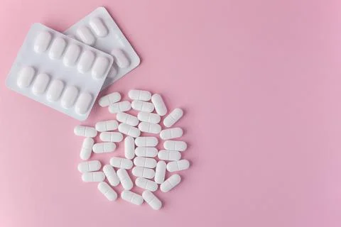 Tabletten or pillen in white package on the pink background with place for .. Stock Photos
